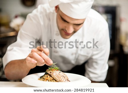 Male chef garnishing his dish, ready to serve
