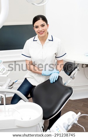 Female dental assistant sitting beside dental chair
