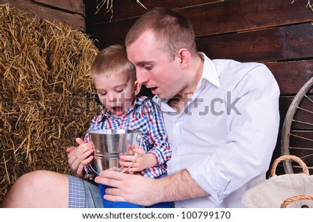 father and son, in a shed on straw. in the hands of a small bucket. People are surprised emotionally