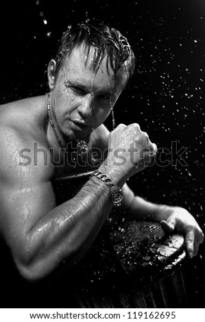 beautiful sports man looks at the camera. splashes of water on his sexy body. black-white portrait