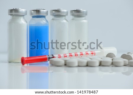 insulin syringe, pills and vials for injection, with white and blue mortar. objects in macro mode