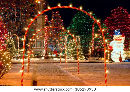Pathway of candy cane arches leading to a brightly lit village Christmas display