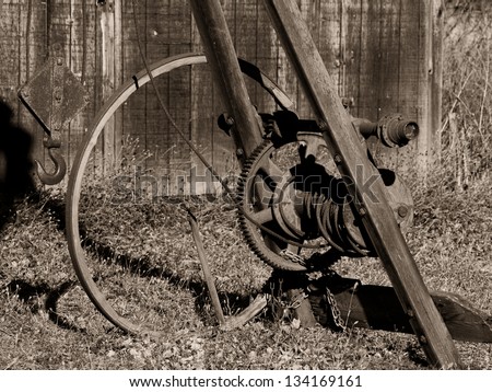 An old winch next to an old shed in sepia-toned black and white