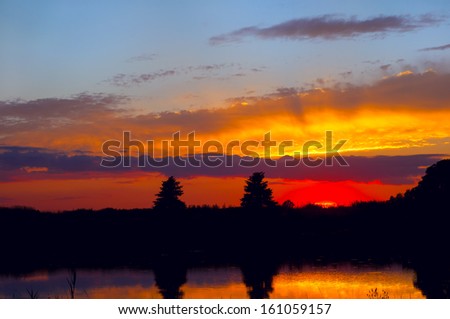 The flaming hues of sunset reflected in clouds and water
