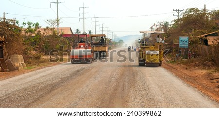 BATTAMBANG PROVINCE, CAMBODIA - FEBRUARY 19 2014: A road construction crew smooths down new gravel on a stretch of the main highway between Seam Reap (location of Angkor Wat) and Battambang.