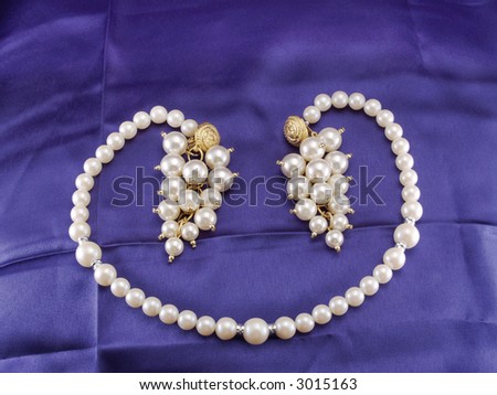 Pearl choker and pearl drop earrings on blue fabric