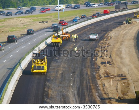 Workers laying asphalt in freeway construction zone