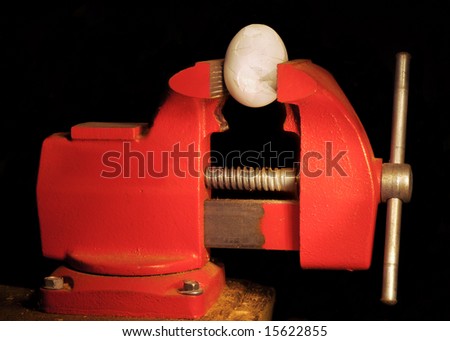 An egg held in a vise cracking under pressure