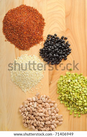 Uncooked quinoa, black beans, pinto beans, and split peas on a cutting board
