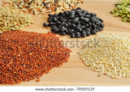 Assortment of dry foods--red and white quinoa, lentils, peas, black beans, and wild rice--on a cutting board