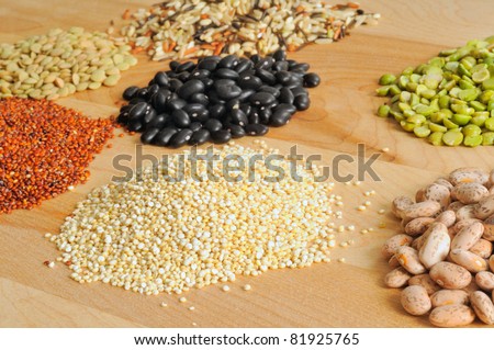Selection of dry foods--red and white quinoa, lentils, peas, beans, and wild rice--on a cutting board