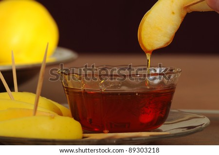 A slice of golden delicious apple drips honey after dipping