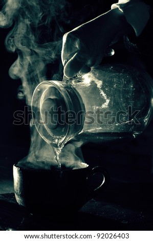 tea pouring from a glass pot, back light duo tone image