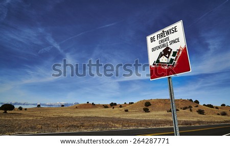 Be firewise road sign reading create defensible space on side of road