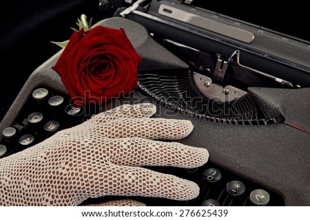 Red rose on typewriter with hand in crocheted glove