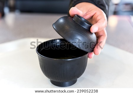 Female hand opens lid of bowl soup