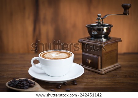 A cup of cafe latte with coffee beans and coffee mill, still life with coffee