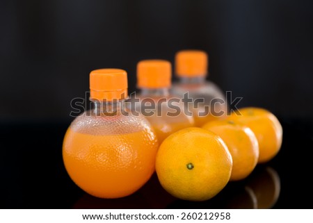Fresh orange drink over black background, orange juice in a bottle and orange on black background
