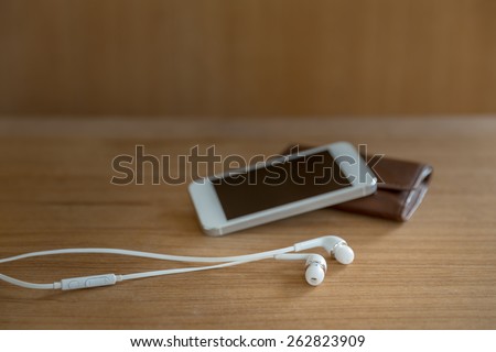 mobile ear phone on wooden background, selective focus on earphones