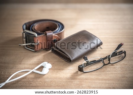 brown wallet,belt, spectacles,earphones  vintage style, selective focus on wallet