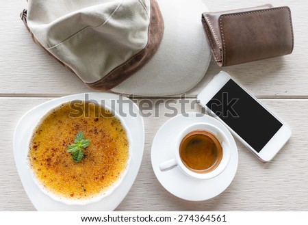 Lie on wooden floor coffee cup and creme brulee on table and mobile phone,wallet