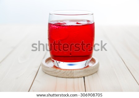 Red drink with ice cubes in a glass, Red soda in glass put on wooden table