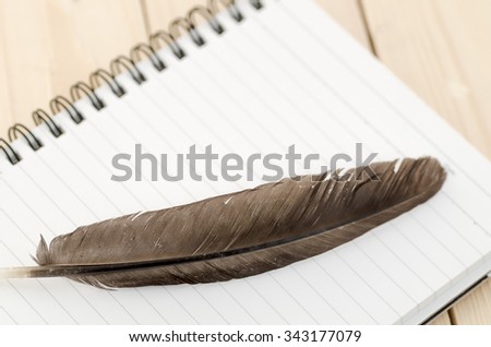 blank notebook with Feather, blank notebook with brown Feather on wooden background, feather on blank notebook