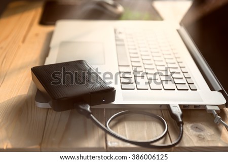 laptop computer with blank screen connecting to black external hard drive, External hard disk and laptop computer, with selective focus
