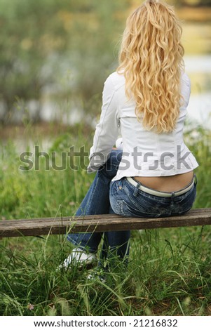 young woman with blond hair sitting on the bench in nature