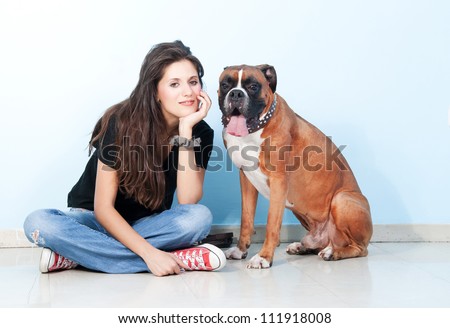 Portrait of Pretty young, happy, woman with her  beautiful Boxer Dog. Studio shoot. Blue , white background
