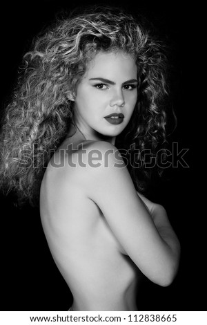Black and white photo of a beautiful, elegant , nude  woman with magnificent long hair . Profile Portrait of feminine with long curly hair .