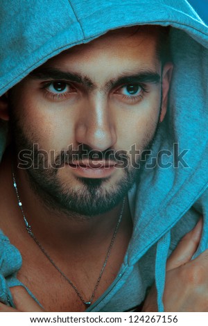 Arabian Man. Good looking male  posing in dangerous style with a hat . Studio Photography. Vertical shot.