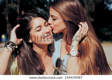 brunette model girl kissing and smile her lovely best friends. outdoors