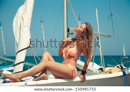 Attractive young girl in bikini posing on a yacht at a sunny summer day. horizontal shot.