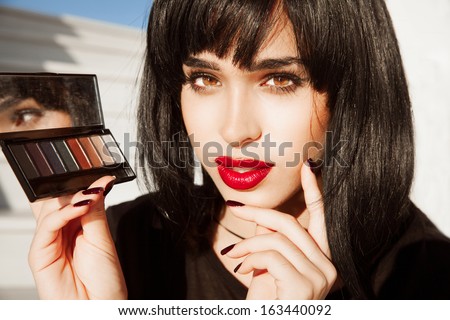 Close-up portrait of beautiful woman with red lipstick and bright make up. Woman with black hair,hairstyle . Red Lipstick. Big Lips. Palette of shadows. Pretty girl in fashion style. Horizontal shot.