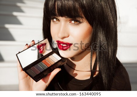 Close-up portrait of beautiful woman with red lipstick and bright make up. Woman with black hair , hairstyle . Red Lipstick . Palette of shadows .Pretty girl ,fashion style. Sexy look.Horizontal shot.