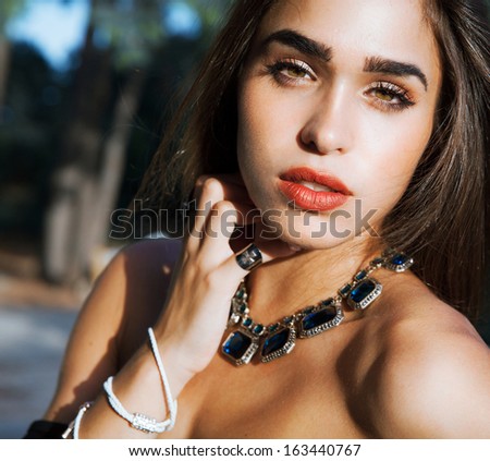 Sensual woman beauty. Jewelry portrait . Woman with bright make up and red lips. Shine healthy skin.Fashion portrait . Profile shot. Long shine hair. Sexy look. Outdoors shot. Soft colors