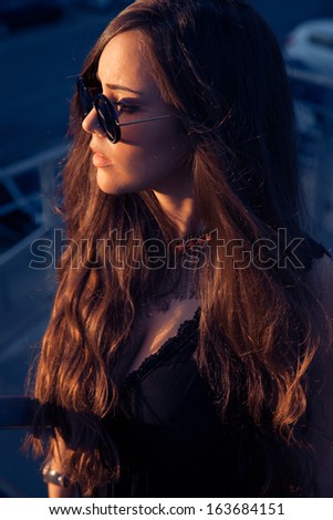 Long hair woman with sunglasses. Expensive sunglasses.Long hair look. Sexy. Profile shot , soft sunny colors.Sunset shot. outdoors shot.  Blue Colors of background.Urban - street style. Vertical Image