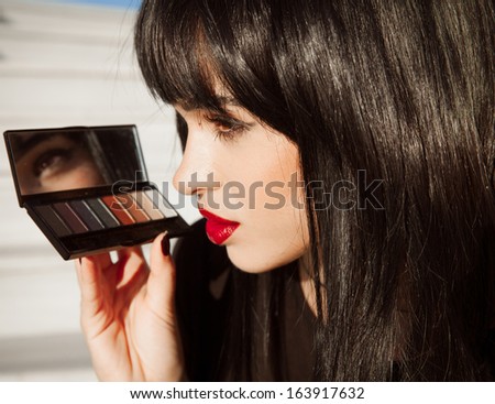 Make up portrait of beautiful woman with red lipstick and bright make up. Woman with black hair , hairstyle . Red Lipstick . Palette of shadows .Pretty girl ,fashion style. Sexy look.Horizontal shot.