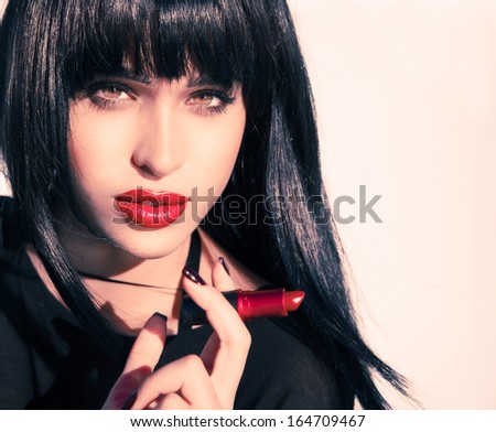 Sensual young female with shine hair holding a lipstick . Make up concept.Shiny hair. Healthy skin . Asian pure beauty. Red lipstick . horizontal shot over a white background.