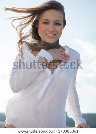 Portrait of beautiful girl, the wind fluttering hair. Clouds sky, soft colors. Outdoors shot