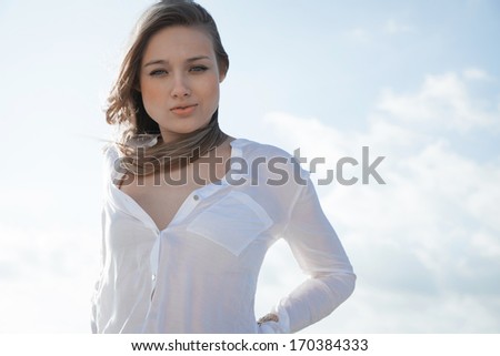 Beautiful  young girl, the wind fluttering hair. Clouds sky, soft colors. Outdoors shot