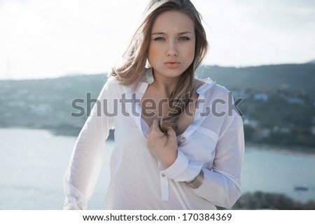 Beautiful  young girl, the wind fluttering hair. Clouds sky, soft colors. Outdoors shot