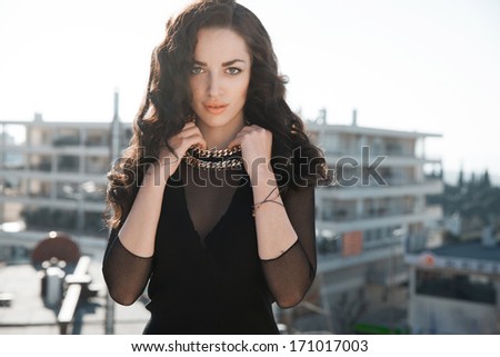 Beautiful brunette woman with long black wavy hair and black outfits. Bright make up face .Sexy look. Street style. Vertical shot.
