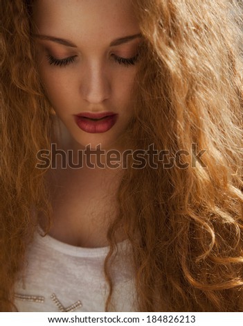 Beautiful Blonde with long curly shine hair and make up. Female with wavy hair and bright make up. vertical shot, studio