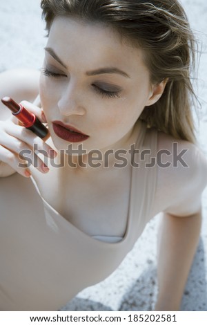 attractive woman with a red lipstick and wet look. vertical shot. outdoors