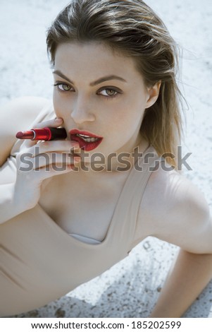 attractive woman with a red lipstick and wet look. vertical shot. outdoors