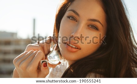 Young woman applying perfume on herself isolated on white background. Fashion photo, outdoors shot. horizontal.