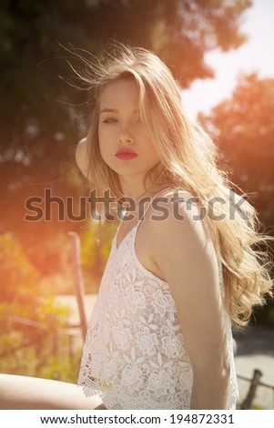 profile shot of beautiful exotic blonde with long blond curly hair. vertical shot in summer outfits. Toned in a warm colors.Backlight