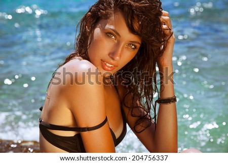 beautiful brunette with wet look and bright makeup by the sea. Toned in warm colors. horizontal shot, outdoors